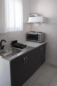 a kitchen with a sink and a microwave at Matinas rooms in Nea Mesangala