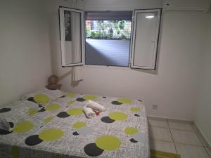 a bedroom with a bed with polka dot sheets and a window at Bungalow Milo in Bouillante