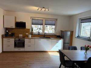 a kitchen with white cabinets and a wooden table at Ferienwohnung Alpenblick in Wessobrunn
