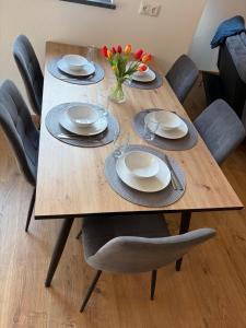 a wooden table with plates and flowers on it at Ferienwohnung Alpenblick in Wessobrunn