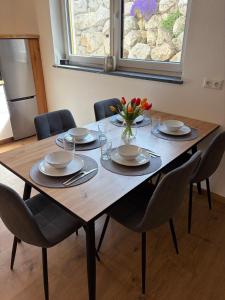 a wooden table with chairs and a vase of flowers on it at Ferienwohnung Alpenblick in Wessobrunn