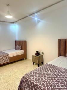 a bedroom with two beds and a night stand with a table at Bord de Mer kelibia ezzahra in Ḩammām al Ghazzāz
