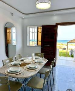 a dining room with a table and chairs and the ocean at Bord de Mer kelibia ezzahra in Ḩammām al Ghazzāz