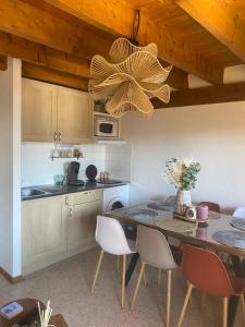 a kitchen with a table with chairs and a chandelier at Le cosy d Asmae in Ustou