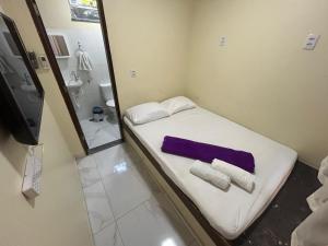 a small room with a bed with towels and a mirror at Village enseada do castelo-com carregador de carros eletricos in Praia do Forte