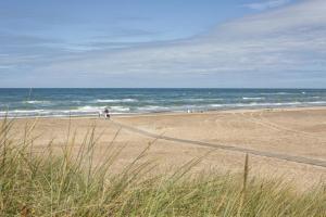 a beach with people walking on the sand and the ocean at DCU-Camping Tranum in Brovst +4 photos