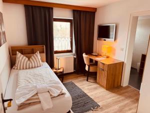 a bedroom with a bed and a desk and a television at König Ludwig Stub´n in Prien am Chiemsee