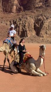 two people riding on a camel in the desert at Desert Time in Wadi Rum
