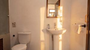 a white bathroom with a toilet and a sink at Aduana House in Santa Teresa Beach