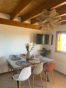 a dining room table with chairs and a chandelier at Le cosy d Asmae in Ustou