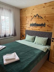 a bedroom with a green bed with a wooden wall at Apartments S&S in Žabljak