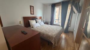 a bedroom with a bed and a desk and a window at Ale Galicia in Cambre
