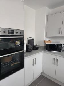 a kitchen with white cabinets and a black microwave at HomeAway Comfort in Minster