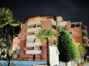a tall building with a palm tree in front of it at Bogdani Apartment in Golem