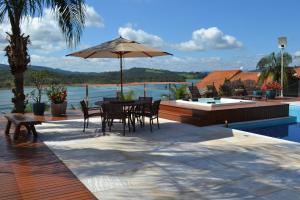 a patio with a table and chairs and an umbrella at Pousada Suítes do Lago in Capitólio