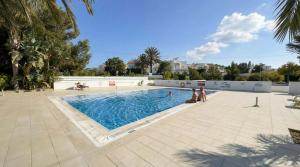 a swimming pool with two people standing around it at Coralli Beachfront 1BDR Protaras in Paralimni