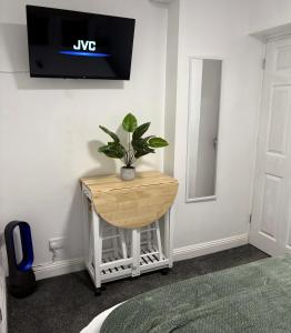 a tv on a wall with a plant on a table at The Snug Guestroom Poole in Poole