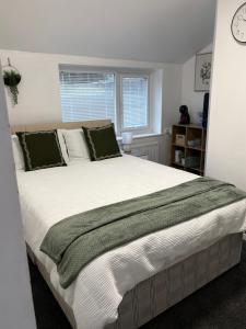 a bedroom with a large white bed with green pillows at The Snug Guestroom Poole in Poole