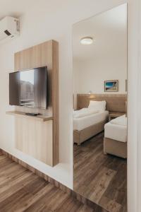 a room with two beds and a tv and a mirror at Lavanda Rooms & Apartment - Malinska in Malinska