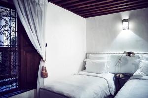 a white bedroom with two beds and a lamp at Riad chak chak suite & spa in Fez