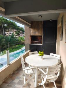 a white table and chairs on a balcony with a pool at Amarras pinamar in Pinamar