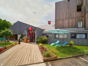 a building with a yard with a bench and an umbrella at ibis Nemours in Nemours