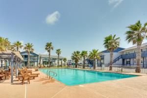 a swimming pool with tables and chairs and palm trees at 'Sea-King Sol' Ocean-View Condo in Port Aransas! in Port Aransas