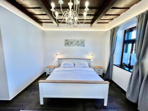 a bedroom with a white bed and a chandelier at Antik Vendégház in Nagyvisnyó +152 photos