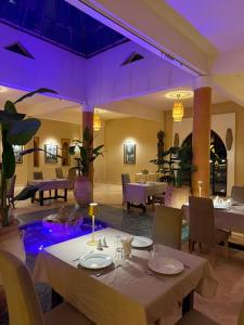 a restaurant with tables and chairs and purple lighting at Sbai Palace in Mhamid