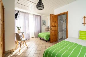 a bedroom with a green bed and a table and a bathroom at Dom Czajka nad Jeziorem Wigry in Stary Folwark