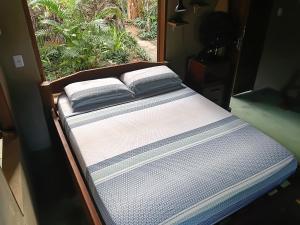 a bed with two pillows on it in front of a window at Recanto BantuArte-Boipeba in Cairu