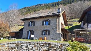 a stone house on a hill with a stone wall at Casa Rongia in Faido