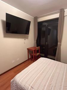 a bedroom with a bed and a television on the wall at Hotel Makita in Muquiyauyo