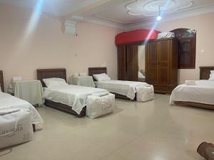 a room with four beds and a wooden cabinet at Adam House in Ghardaïa