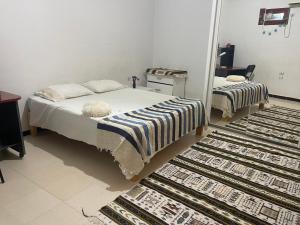 a bedroom with a bed and two rugs on the floor at Adam House in Ghardaïa