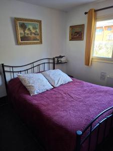 a bed with a purple comforter in a bedroom at Vakantiehuis Malaika in Rendeux