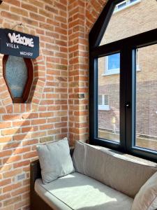 a couch in front of a brick wall with a window at VILLA MICHRY Koksijde 4 adultes 2 enfants proche digue et centre in Koksijde +37 photos