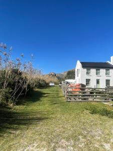 a white house with a fence in front of it at Waterberry Hideaway in Pringle Bay