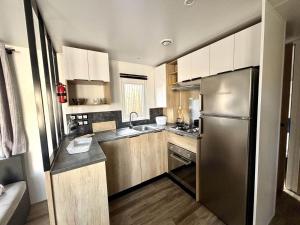 a kitchen with a stainless steel refrigerator and wooden cabinets at Mobilhome in Saint-Gérons