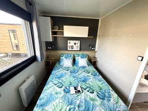 a small bedroom with a bed with blue sheets and pillows at Mobilhome in Saint-Gérons