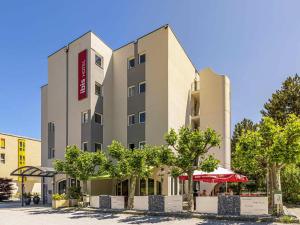 a hotel building with trees in front of it at Ibis Sion in Sion
