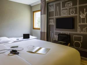 a hotel room with a bed and a tv at Ibis Sion in Sion