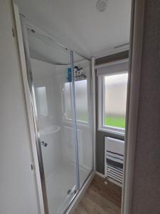 a bathroom with a shower and a sink and a window at D&A Southview getaway in Skegness