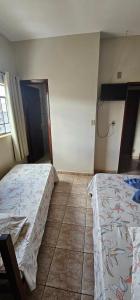 a bedroom with two beds and a tiled floor at Hotel Monarca Paracatu in Paracatu