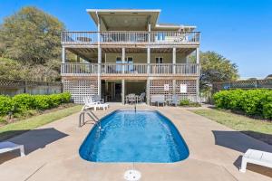 a house with a swimming pool in front of a house at The Sand Wedge in Kitty Hawk