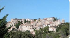 a group of buildings on a hill with trees at Balcon sur le Luberon in Lurs