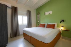 a bedroom with a large bed with a green wall at Trupial - The green flamingo in Willibrordus
