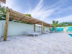 a patio with two white chairs and a wooden roof at Trupial - The green flamingo in Willibrordus