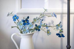 a white vase with blue flowers in it at Valhalla The Nest in Vesuvius