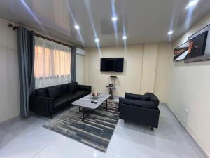 a living room with two black couches and a tv at Moima Plaza Guesthouse in Monrovia